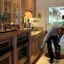 Roach control technician applying kitchen treatment along baseboards in {city}, {state}
